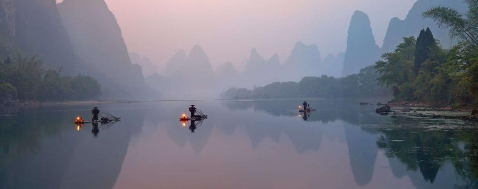 Fleuve Li à Xingping, en Chine, avec pêcheurs aux cormorans sur des radeaux de bambou au lever du soleil