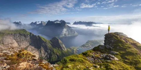 Randonneur sur un promontoire rocheux au lever du soleil dans les îles Lofoten en Norvège