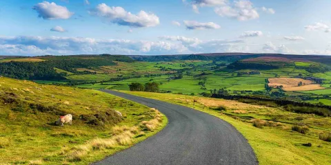 Route panoramique à travers la campagne anglaise illustrant les plus beaux road trips d'Angleterre