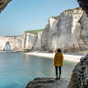 Femme observant les falaises d’Étretat depuis une grotte naturelle sur la côte d’Albâtre en Normandie