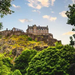 Le château d'Édimbourg dominant Castle Rock au coucher du soleil, vu depuis Princes Street Gardens, en Écosse.