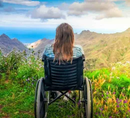 Une femme en chaise roulante admire des montagnes.