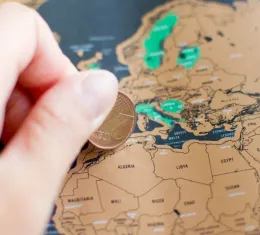 Femme grattant une carte du monde avec une pièce de 2 centimes d’euro