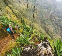 Randonneuse sur un promontoire volcanique dominant une vallée verdoyante et brumeuse à Santo Antão, Cap-Vert