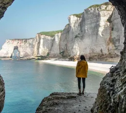 Falaises d’Étretat vues depuis une grotte avec randonneur face à la mer en Normandie