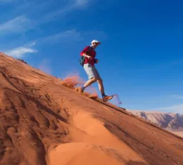 Coureur descendant une dune dans le désert de Wadi Rum en Jordanie, illustration des marathons les plus spectaculaires du monde