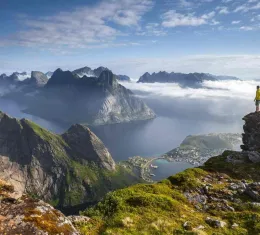 Randonneur sur un promontoire rocheux au lever du soleil dans les îles Lofoten en Norvège