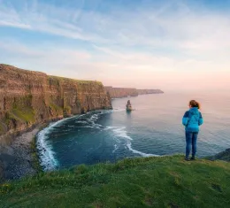 Randonneuse sur le sentier côtier des falaises de Moher face à l’océan Atlantique en Irlande
