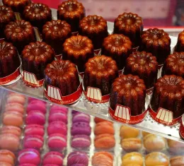 Canelés de Bordeaux en vitrine avec macarons, spécialités sucrées françaises artisanales