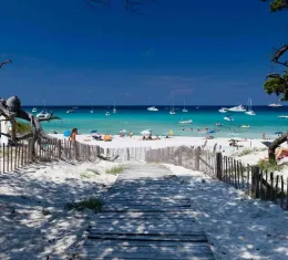 Plage paradisiaque en Corse avec sable blanc, eau turquoise et bateaux