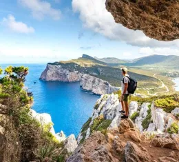 Randonneur admirant les falaises de Capo Caccia depuis un sentier de randonnée en Sardaigne