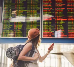 Voyageuse consultant le tableau des départs après un vol annulé ou retardé dans un aéroport.