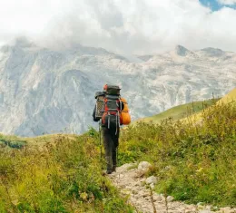 Randonneur avec un sac à dos sur un sentier de montagne pour choisir une randonnée adaptée à son niveau