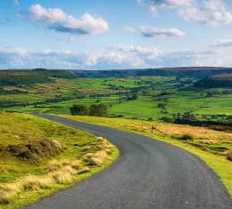 Route panoramique à travers la campagne anglaise illustrant les plus beaux road trips d'Angleterre