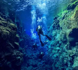 Des plongeurs explorent une spectaculaire faille sous-marine aux eaux cristallines, illustrant les plus beaux sites de plongée dans le monde.