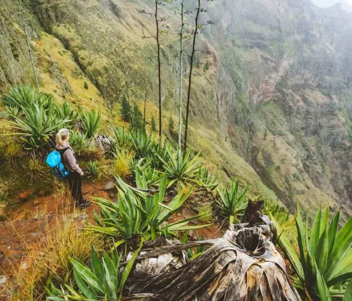 Randonneuse sur un promontoire volcanique dominant une vallée verdoyante et brumeuse à Santo Antão, Cap-Vert