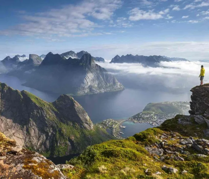 Randonneur sur un promontoire rocheux au lever du soleil dans les îles Lofoten en Norvège