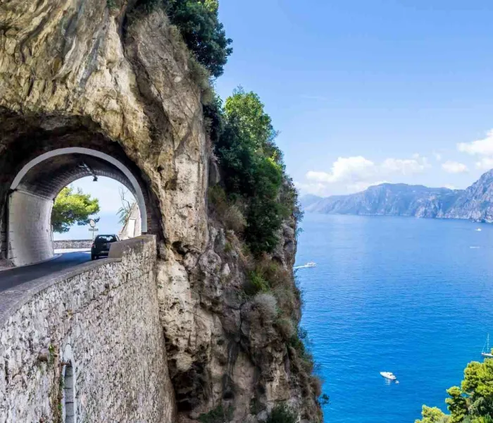 Route panoramique de la côte amalfitaine creusée dans la falaise au-dessus de la mer Méditerranée, l’un des plus beaux road trips en Italie.