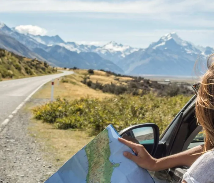 Femme regardant une carte dans une voiture lors d’un road trip sur l’île du Sud en Nouvelle-Zélande