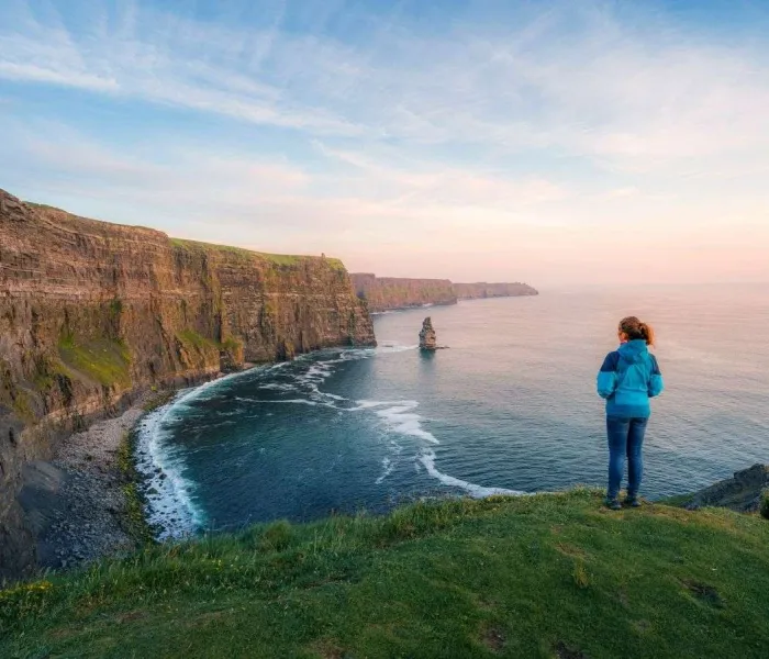 Randonneuse sur le sentier côtier des falaises de Moher face à l’océan Atlantique en Irlande