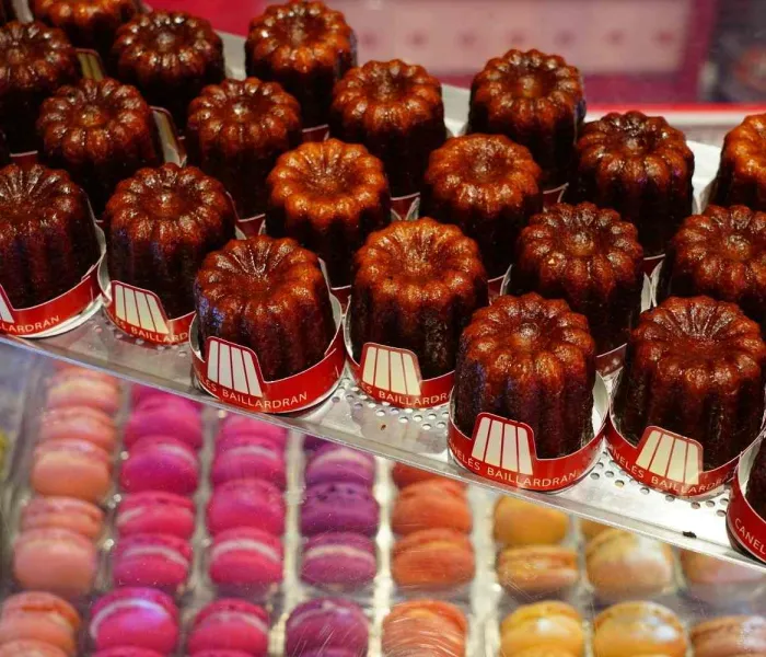 Canelés de Bordeaux en vitrine avec macarons, spécialités sucrées françaises artisanales
