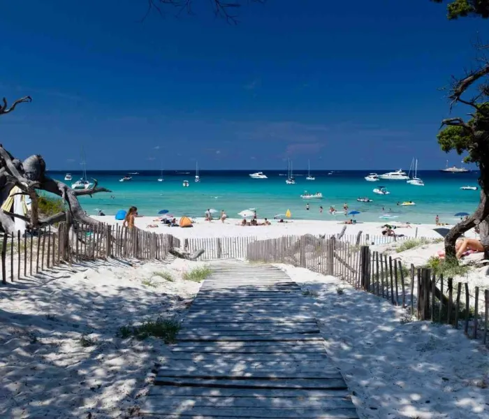 Plage paradisiaque en Corse avec sable blanc, eau turquoise et bateaux