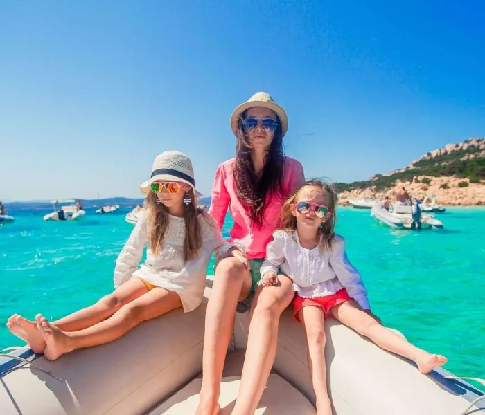 Une mère avec ses enfants en bateau dans les eaux turquoise de Sardaigne pendant les vacances