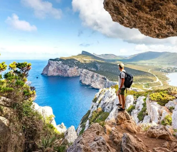 Randonneur admirant les falaises de Capo Caccia depuis un sentier de randonnée en Sardaigne