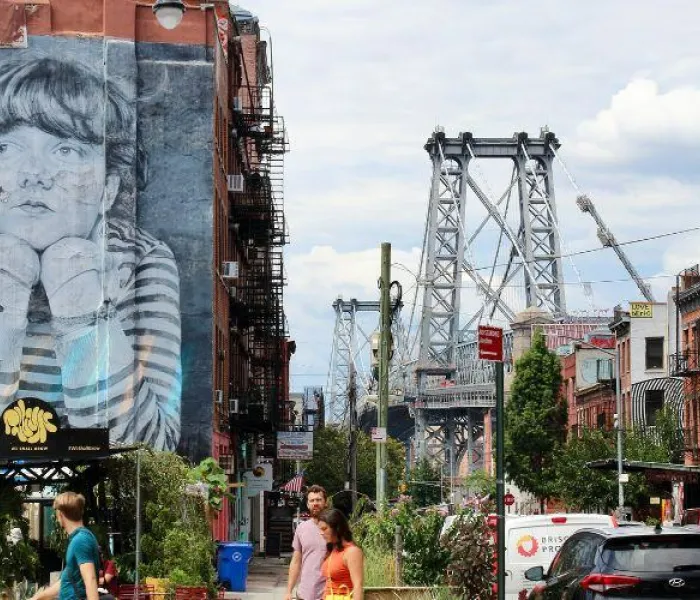 Rue animée de Williamsburg à Brooklyn avec le pont de Williamsburg et une fresque de street art en arrière-plan