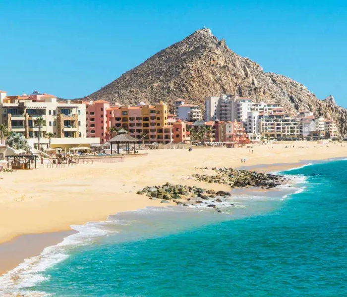 Vue de la plage El Médano à Los Cabos en Basse-Californie, avec les hôtels en bord de mer et les montagnes désertiques