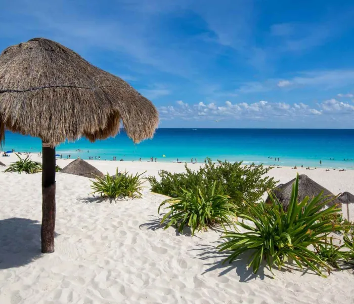 Plage de sable blanc avec palapas et eaux turquoise à Cancún au Mexique