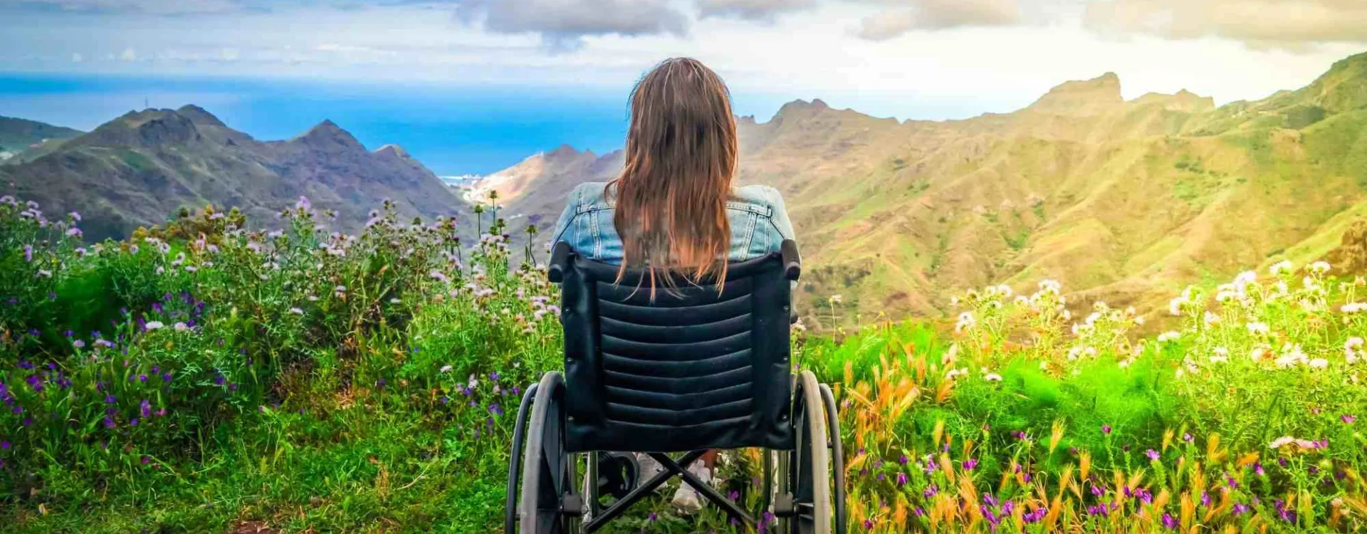 Une femme en chaise roulante admire des montagnes.