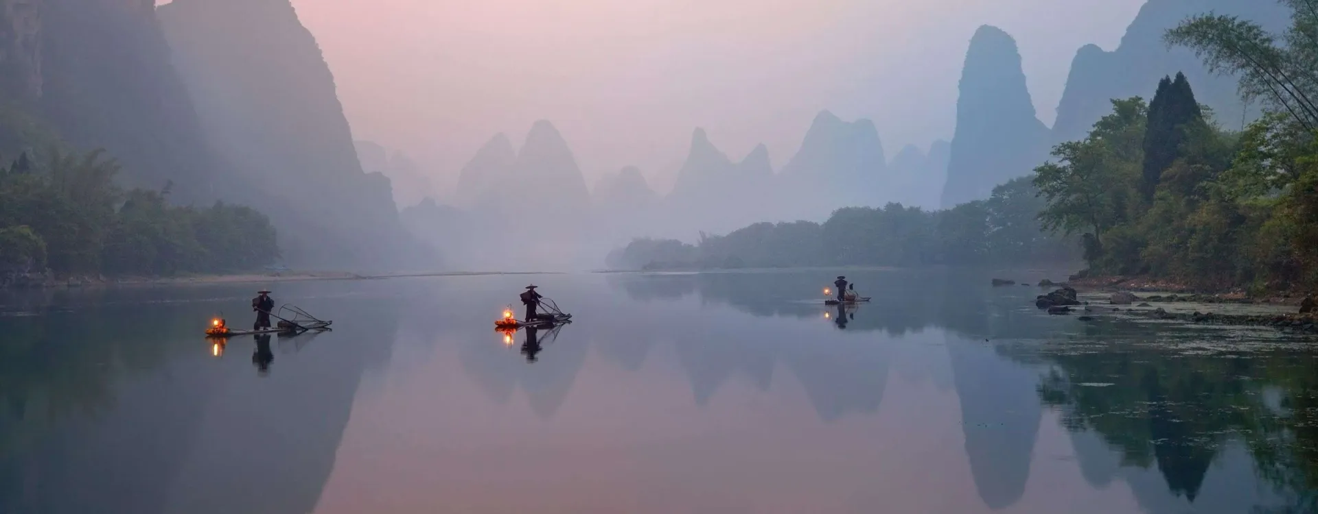 Fleuve Li à Xingping, en Chine, avec pêcheurs aux cormorans sur des radeaux de bambou au lever du soleil