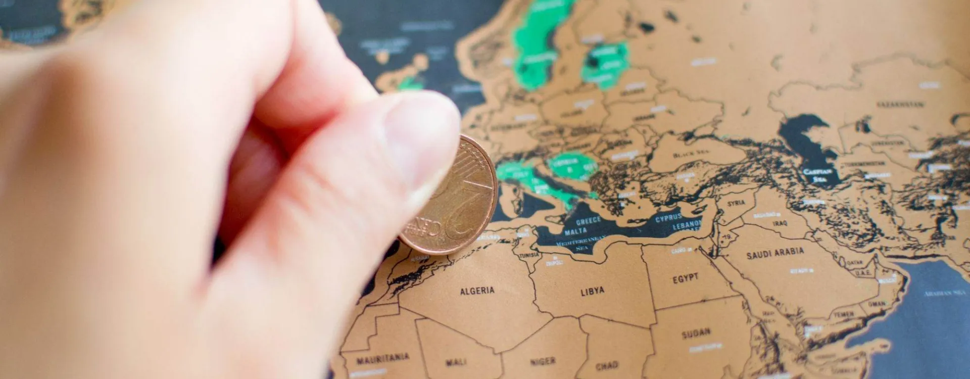 Femme grattant une carte du monde avec une pièce de 2 centimes d’euro