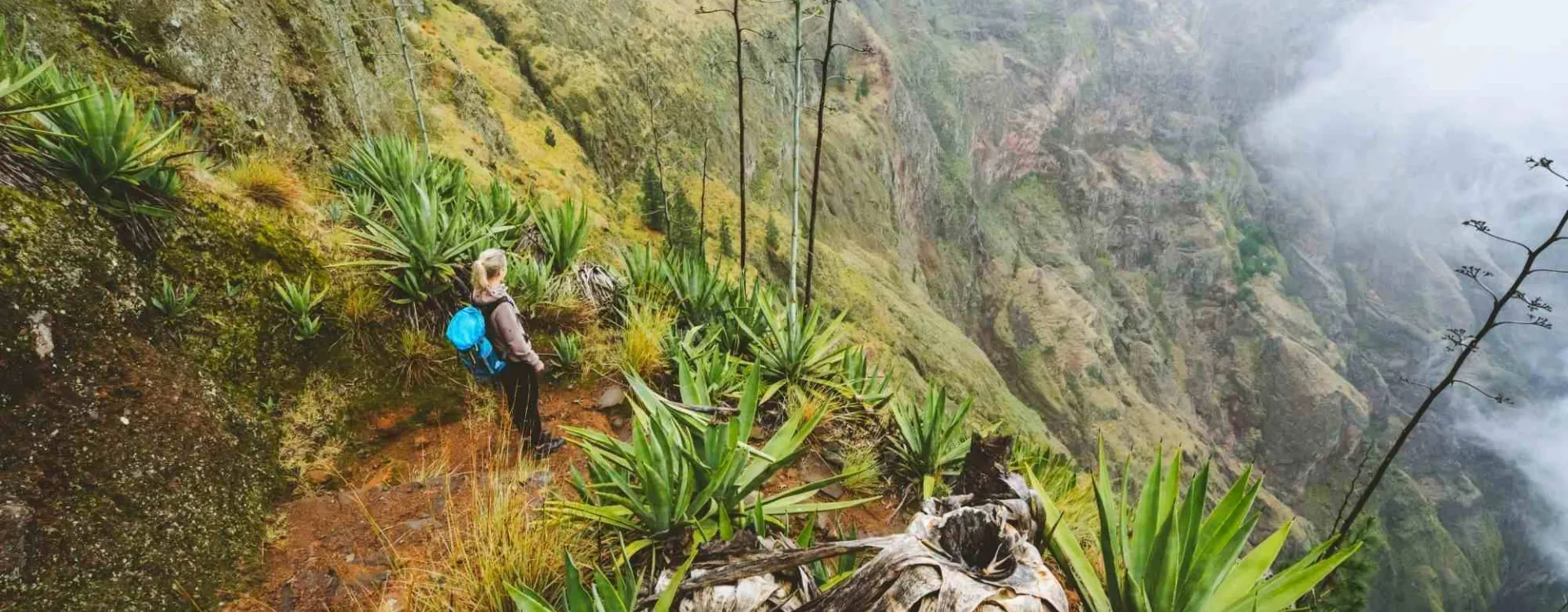 Randonneuse sur un promontoire volcanique dominant une vallée verdoyante et brumeuse à Santo Antão, Cap-Vert