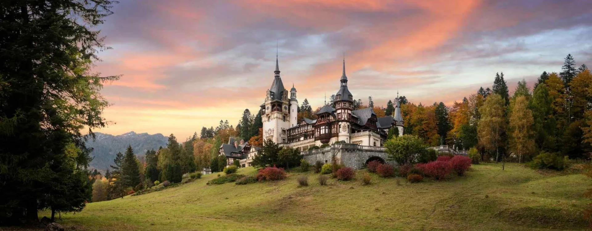 Panorama du château de Peleș en Transylvanie, Roumanie, célèbre château royal entouré de jardins, dans les Carpates au coucher du soleil
