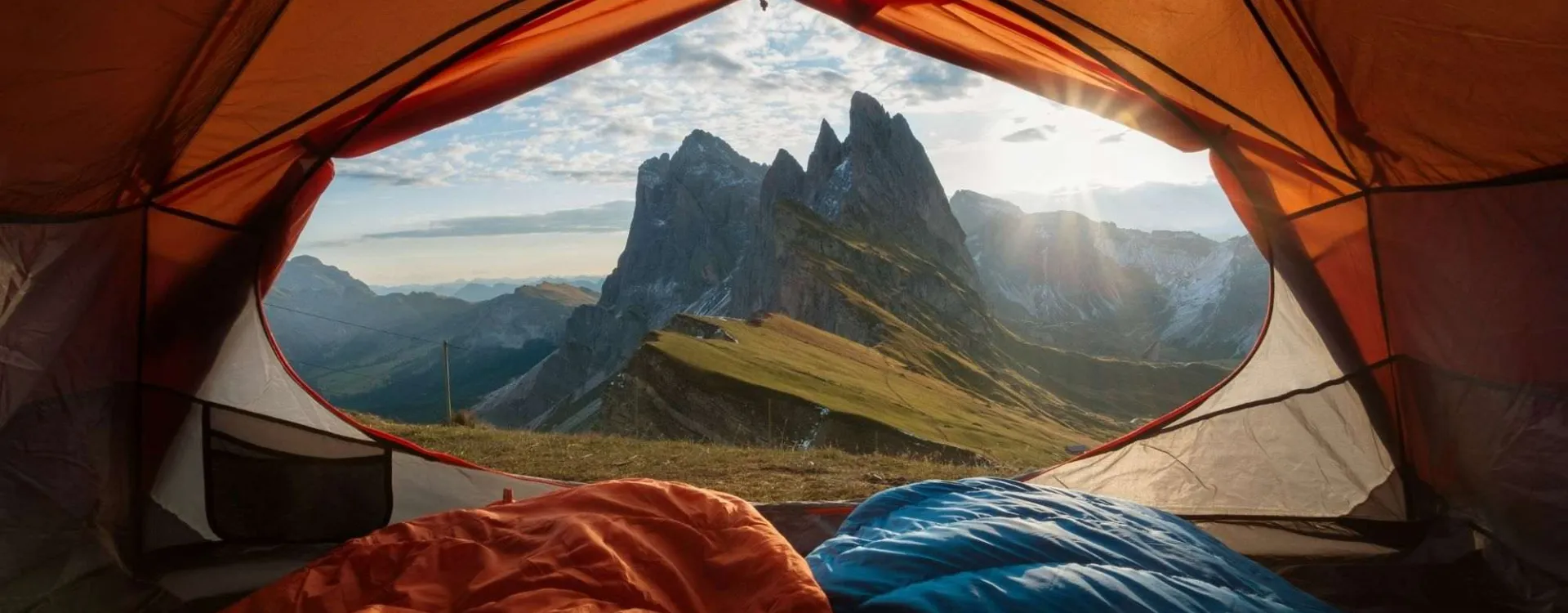 Vue depuis l’intérieur d’une tente de camping, illustrant l’attrait du camping nature et des vacances en plein air.