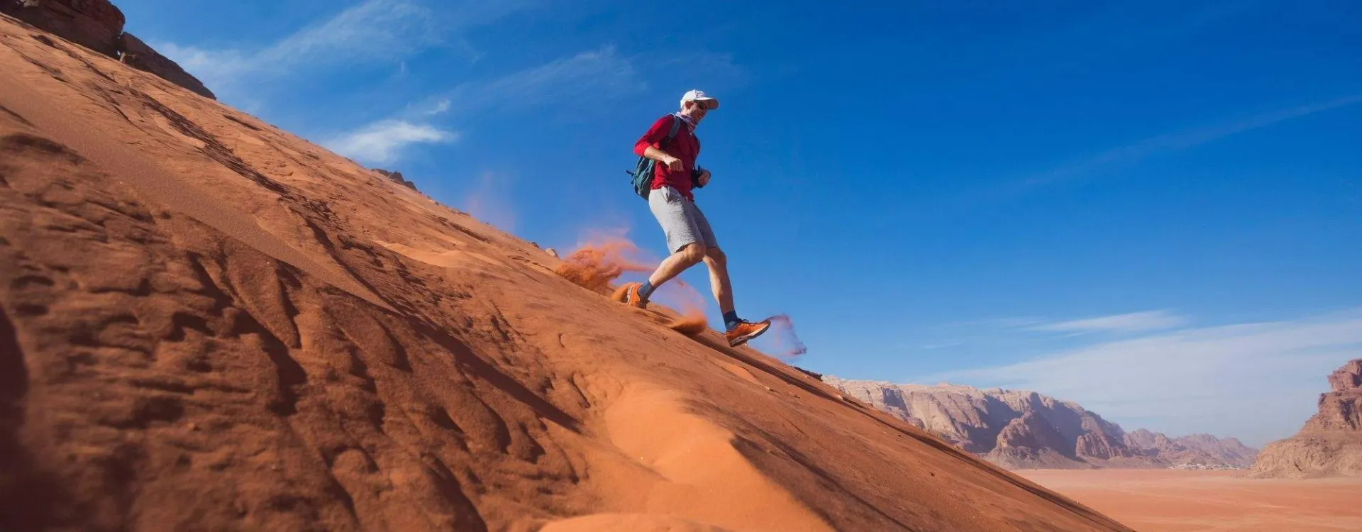 Coureur descendant une dune dans le désert de Wadi Rum en Jordanie, illustration des marathons les plus spectaculaires du monde