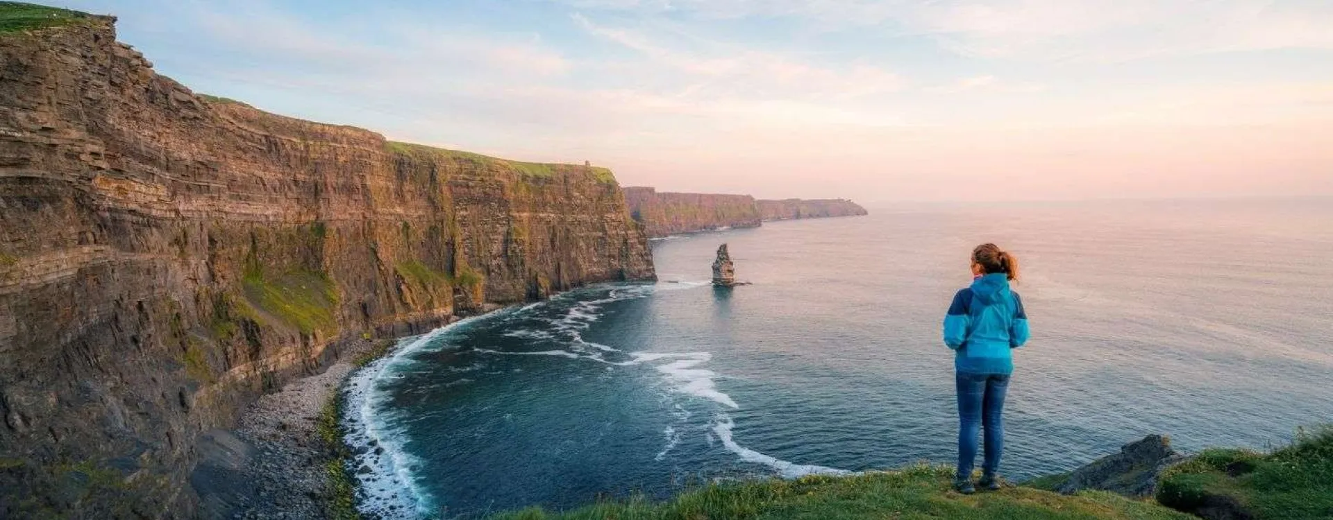 Randonneuse sur le sentier côtier des falaises de Moher face à l’océan Atlantique en Irlande