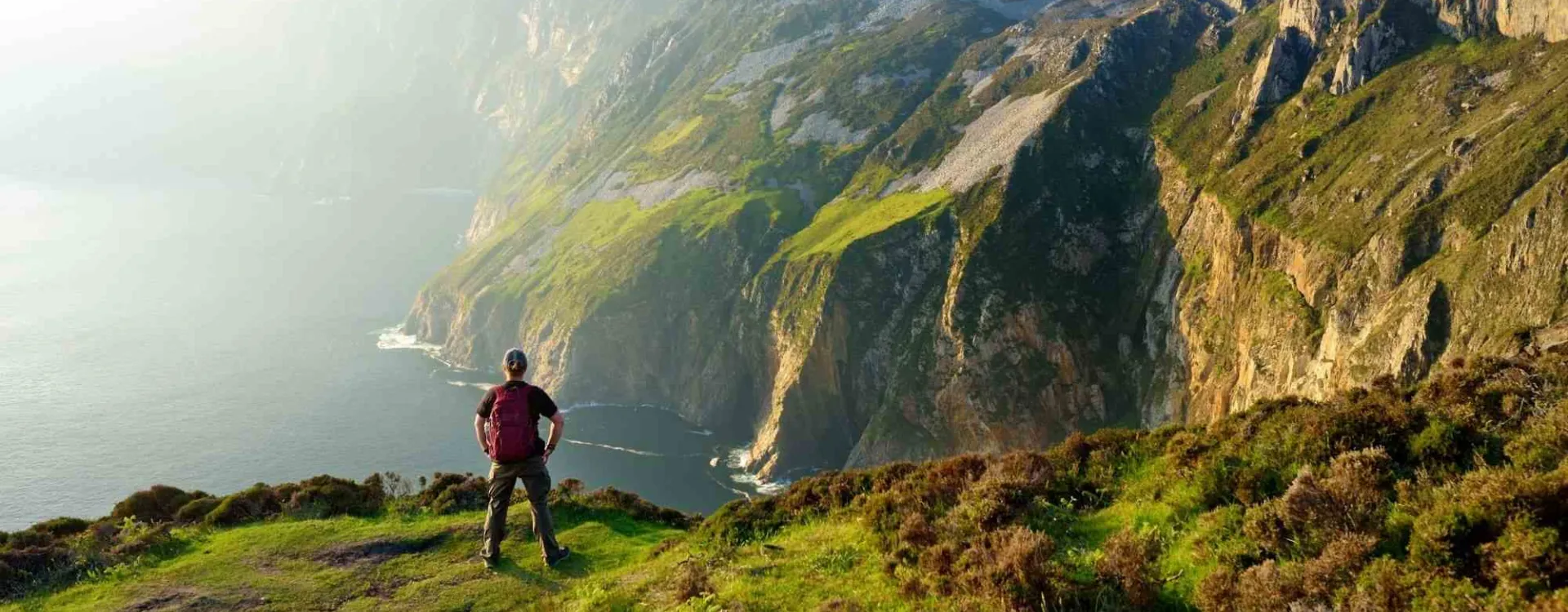 Randonneur face aux falaises spectaculaires de Slieve League, l'une des plus belles randonnées d'Irlande.