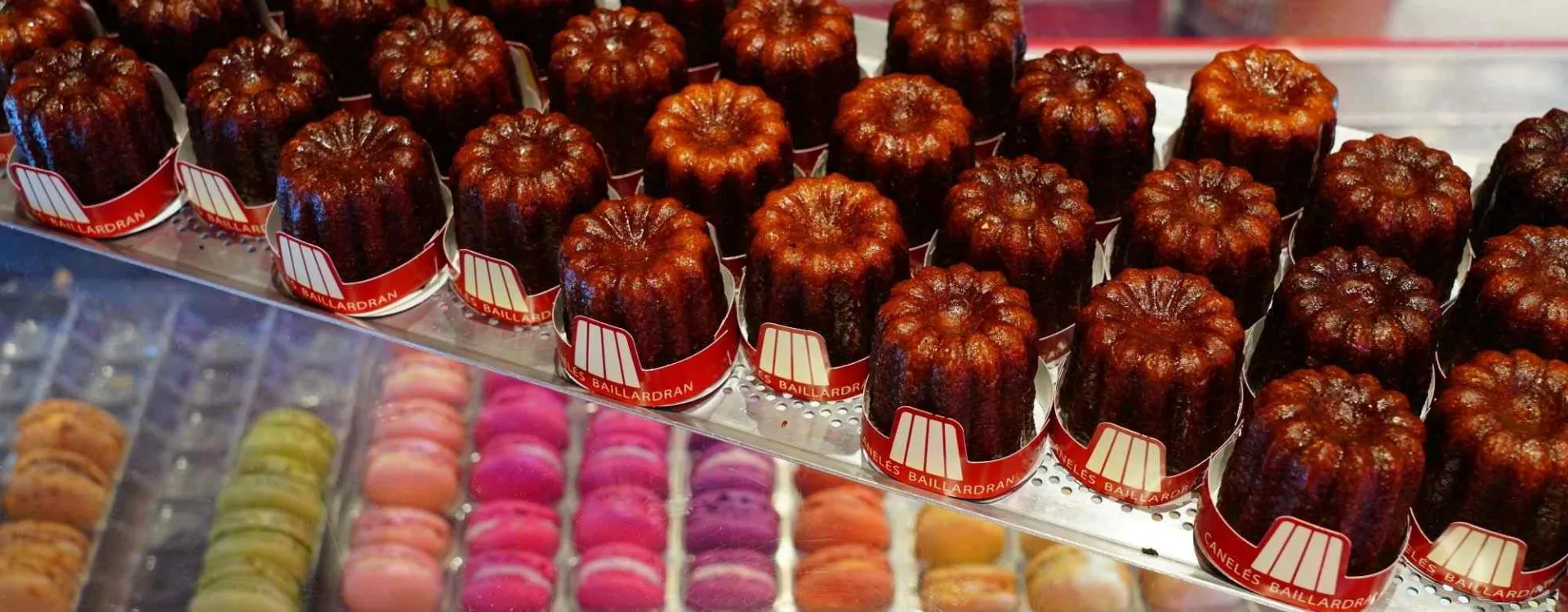 Canelés de Bordeaux en vitrine avec macarons, spécialités sucrées françaises artisanales