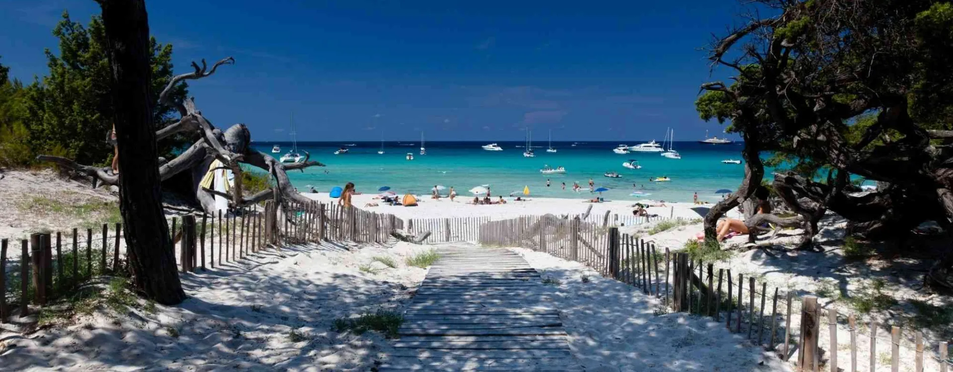 Plage paradisiaque en Corse avec sable blanc, eau turquoise et bateaux