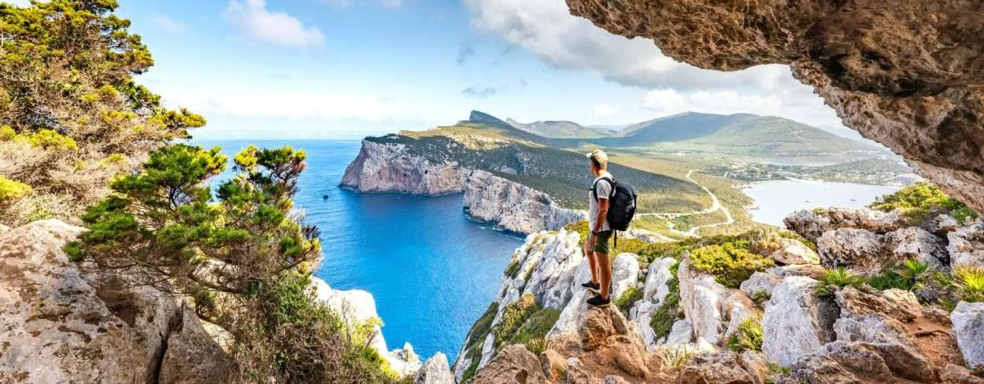 Randonneur admirant les falaises de Capo Caccia depuis un sentier de randonnée en Sardaigne
