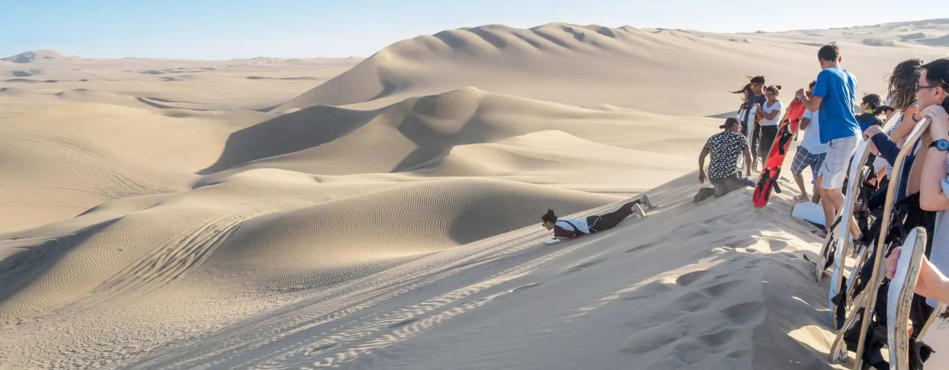 es voyageurs descendent les dunes du Cerro Blanco en sandboard dans le désert de Sechura, au Pérou.