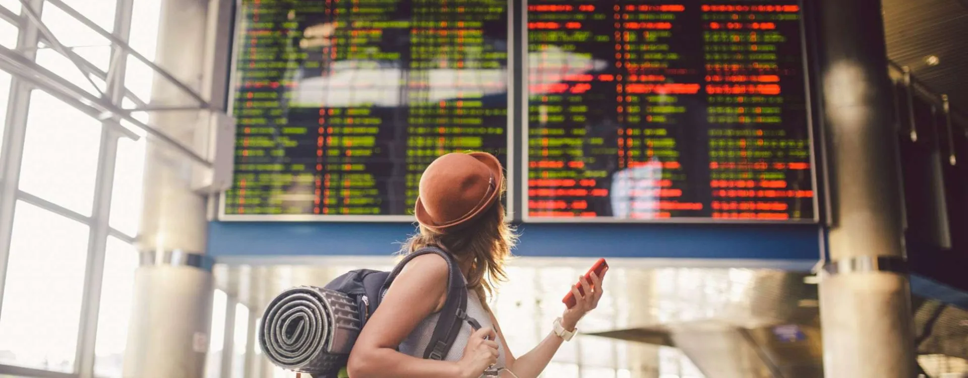 Voyageuse consultant le tableau des départs après un vol annulé ou retardé dans un aéroport.