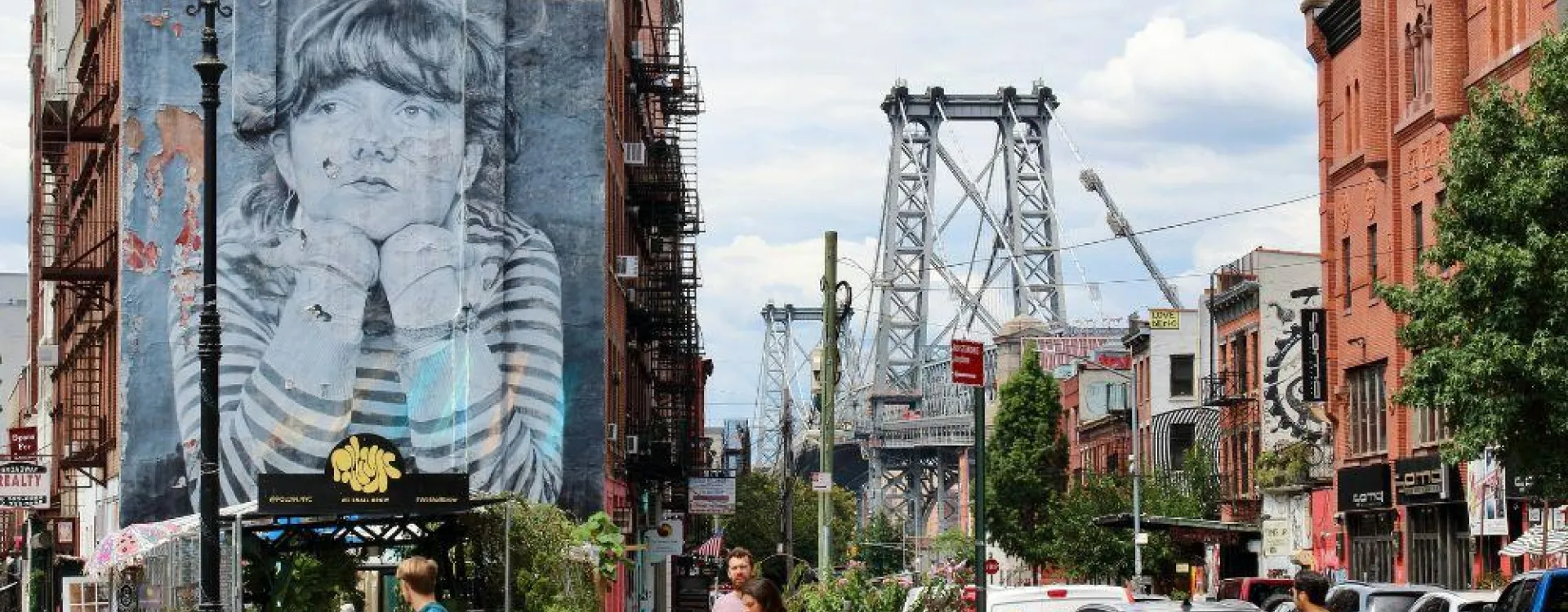 Rue animée de Williamsburg à Brooklyn avec le pont de Williamsburg et une fresque de street art en arrière-plan