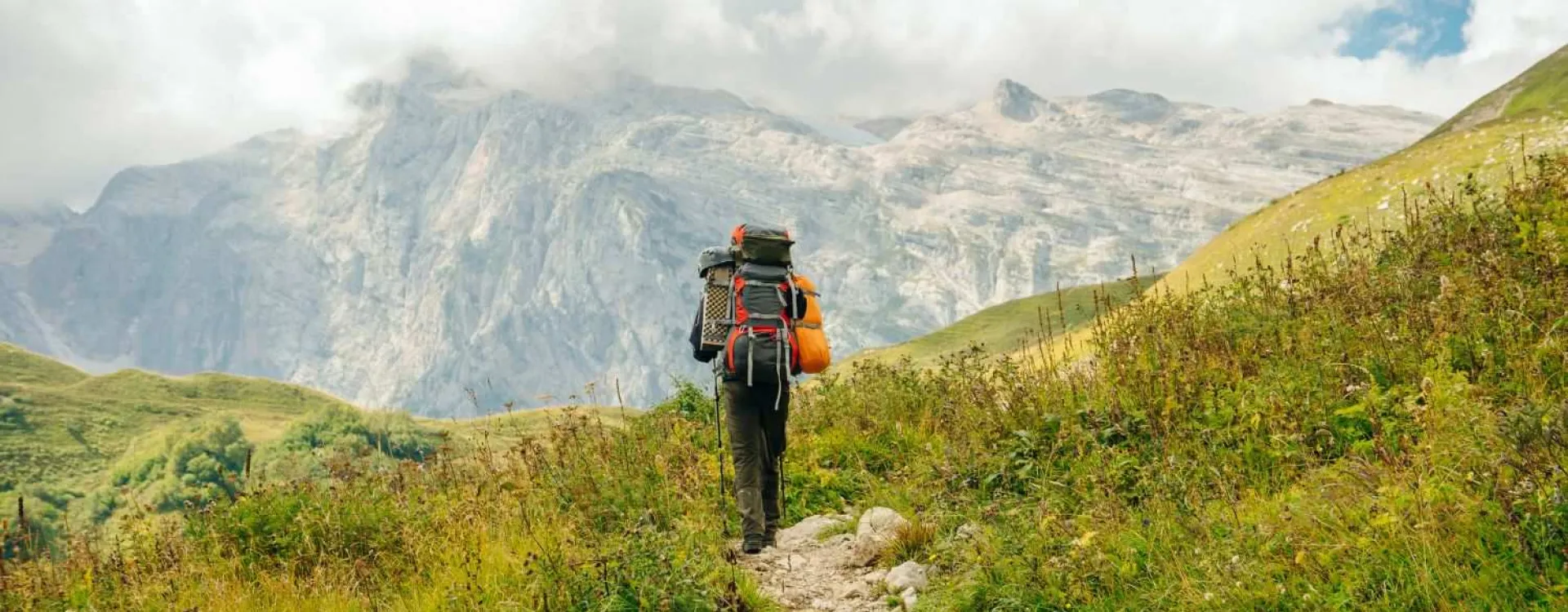 Randonneur avec un sac à dos sur un sentier de montagne pour choisir une randonnée adaptée à son niveau