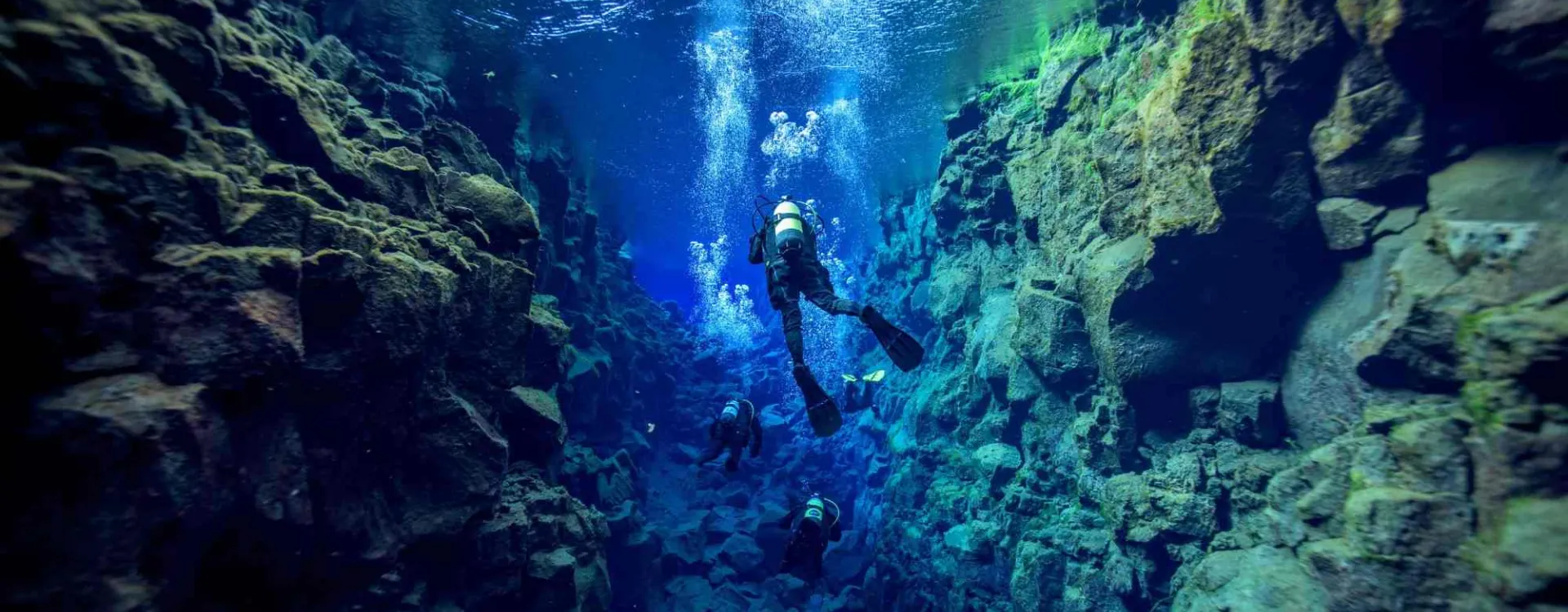 Des plongeurs explorent une spectaculaire faille sous-marine aux eaux cristallines, illustrant les plus beaux sites de plongée dans le monde.
