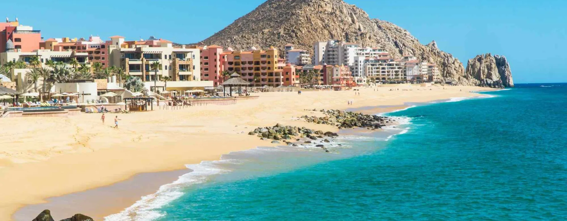 Vue de la plage El Médano à Los Cabos en Basse-Californie, avec les hôtels en bord de mer et les montagnes désertiques