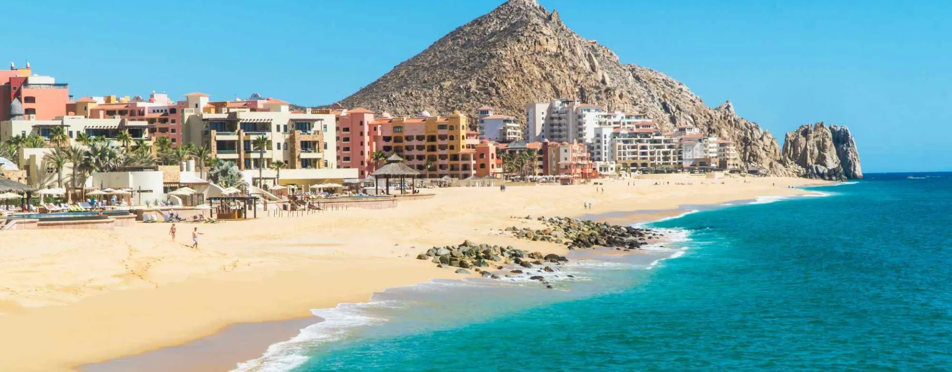 Vue de la plage El Médano à Los Cabos en Basse-Californie, avec les hôtels en bord de mer et les montagnes désertiques